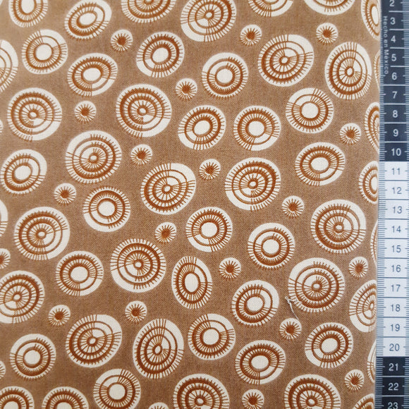 Patchwork stof, brun med uens cirkler og sole.