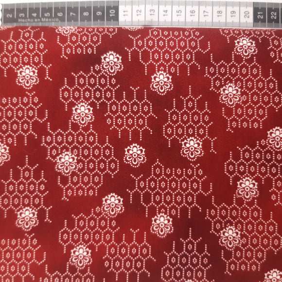 Patchwork stof, rød meleret med små blomster og sekskanter lavet af prikker.