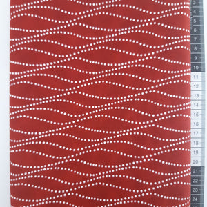 Patchwork stof, mørk rød med hvide prikker som danner bølgende streger