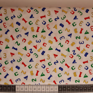 Patchwork stof, hvid med tal og bogstaver i klare farver.