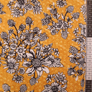 Patchwork stof, gul bikube mønster i bunden og med lyse blomster.