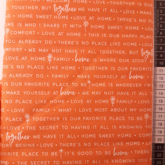 Patchwork stof, orange med lys tekst og bogstaver.