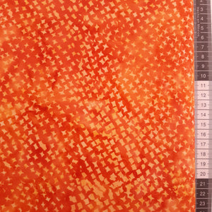Patchwork stof, orange meleret med lyse små spidse figurer der danner mønster.