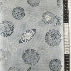 Patchwork stof, lysegrå bund med store julekulger og stjerner i sølv og grålige farver.
