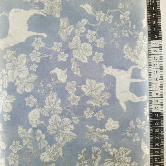 Patchwork stof, støve lyseblå bund med hvide dyr og blomster optegnet med sølv.