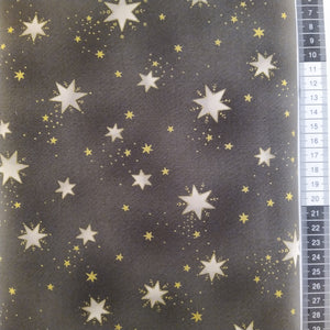 Patchwork stof, grå bund med forskellige størrelser stjerner i lysegrå med guld omkring samt små guld stjerner.