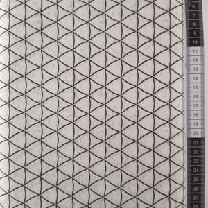 Patchwork stof, rå hvid bund med grafisk mønster med grå trekanter.