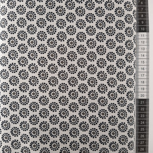 Patchwork stof, råhvid bund, små sorte cirkler med prikker omkring og grå firkant i midten.