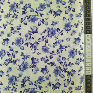 Patchwork stof, hvid bund med store blå og blå/lilla blomster med stilke og blade.
