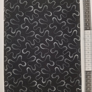 Patchwork stof, sort bund med stort mønstret design i grå og hvide farver.
