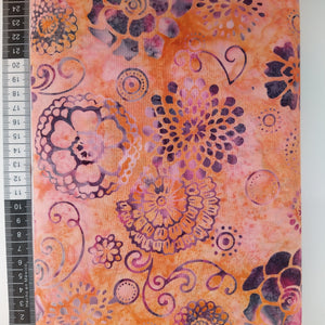 Patchwork stof, multifarvet bund med store dekorative blomster i lilla nuancer.