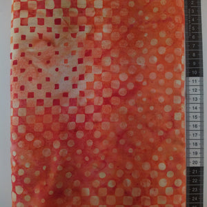 Patchwork stof, orange/rød meleret bund med små firkanter og cirkler.
