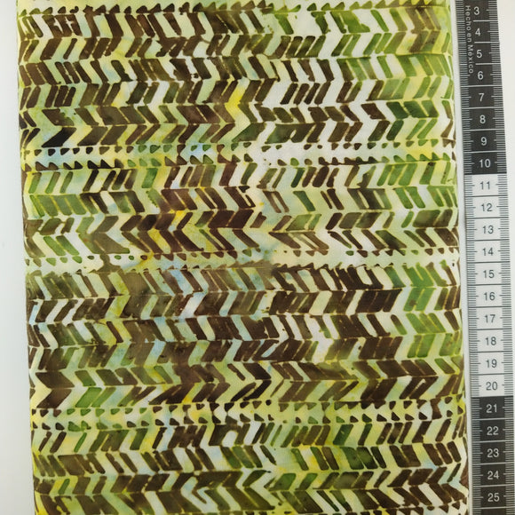 Patchwork stof, lysegul/lysegrøn meleret bund med et stort mønster i grønne og brune farver som ligner spor efter bildæk som går vandret.