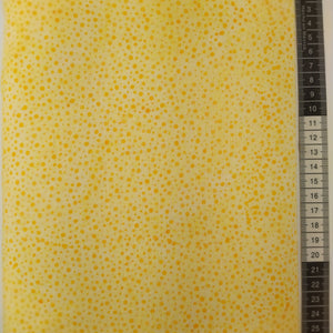 Patchwork stof, lysegul meleret bund med gul/orange små splash prikker.